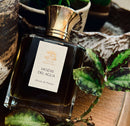 Perfume bottle with gold cap and 'Leone Gentilini' label on a wooden surface with plants.